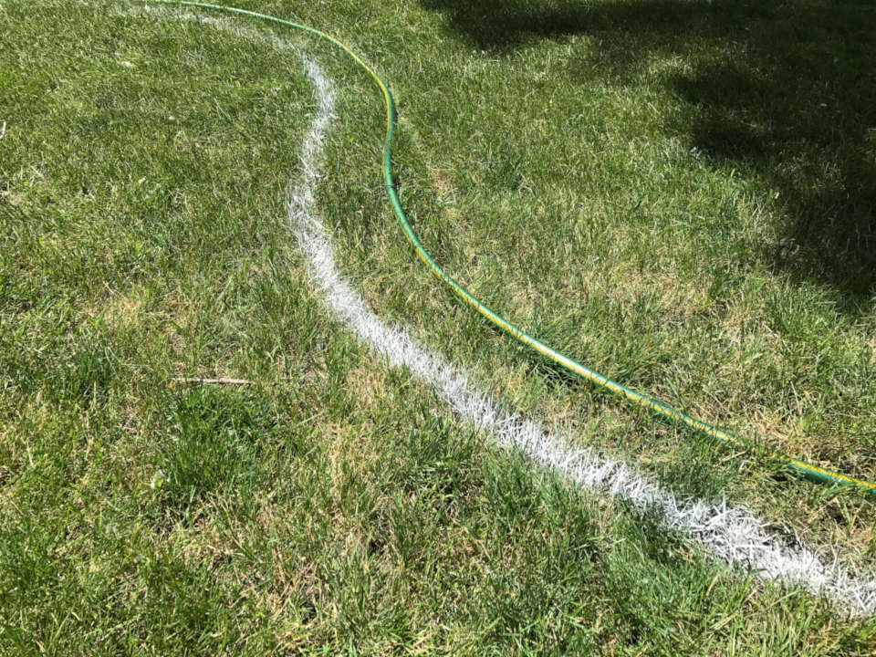 Patio marked out using paint next to garden hose