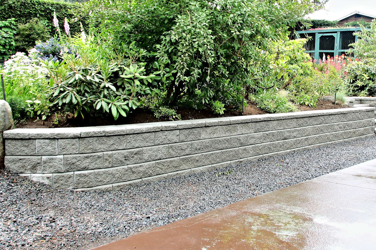 new block retaining wall with plants and shrubs above