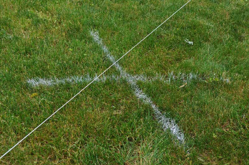 Mason line attached to stakes and an X drawn with layout paint