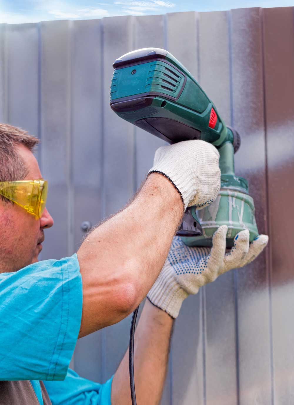 Painter applying stain to a fence using a paint sprayer