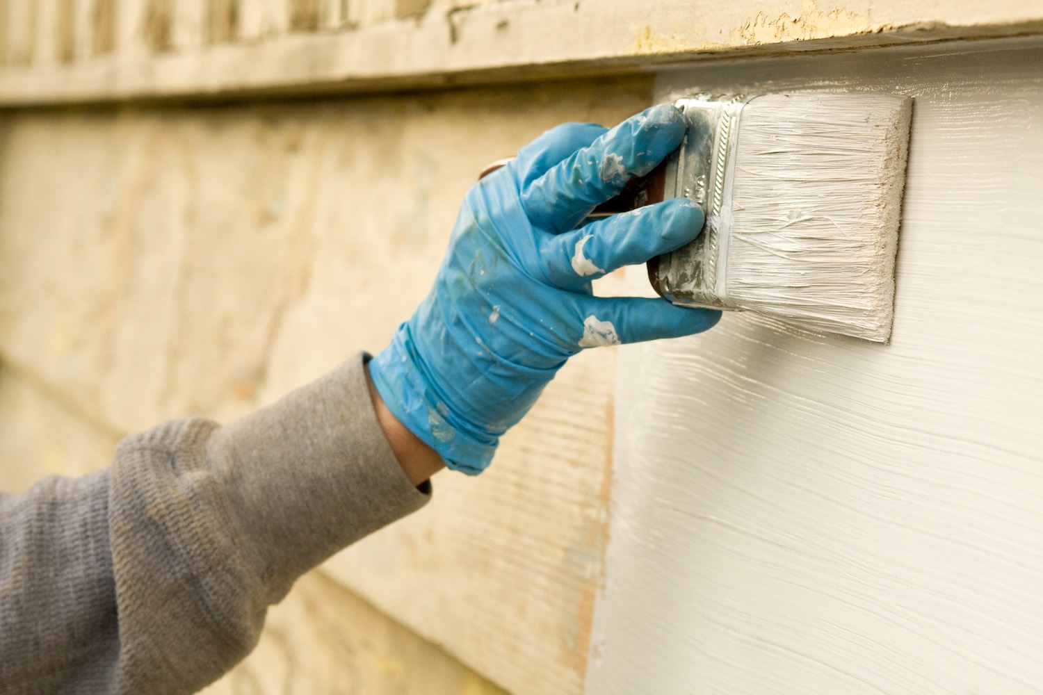 contractor painting the siding of a home